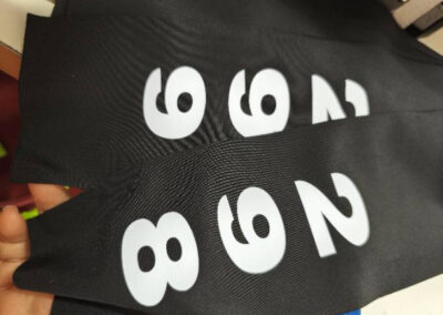 Impression sur mesure des numéros blancs sur le tissu noir des bonnets de natation